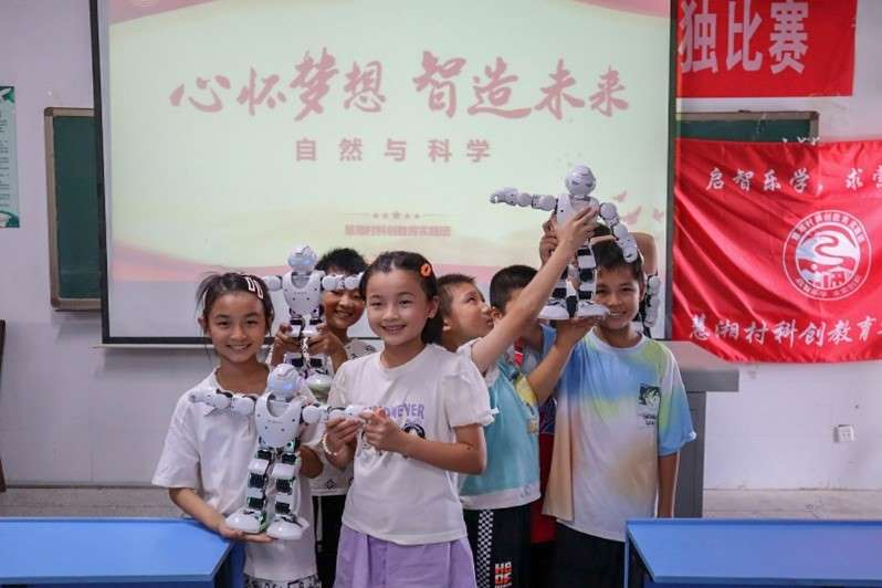 孩子们与机器人合影留念 慧湘村科创教育实践团提供